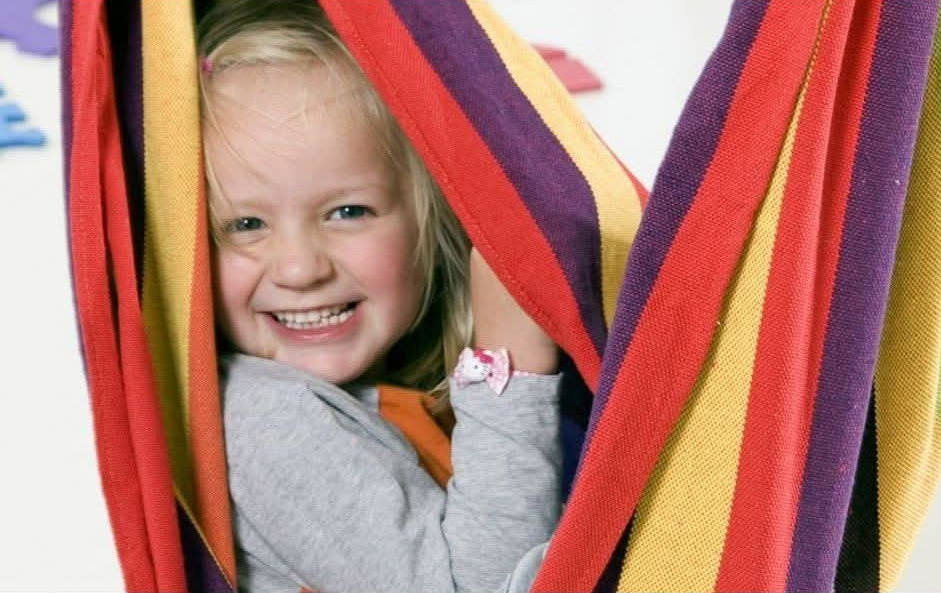 Child peeking through colourful fabric with a happy expression