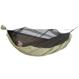 Person lying in a green and black camping hammock with mosquito net on a white background