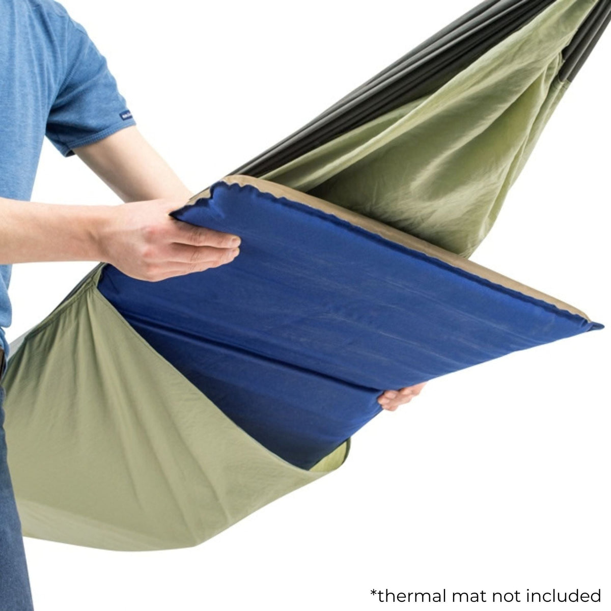 A person is holding up a blue thermal mat insert inside an olive green camping hammock. The image is shot against a clean white background with a small text note in the bottom right corner that says '*thermal mat not included'.