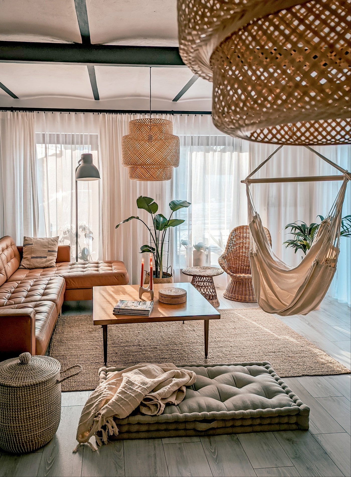 Cosy living room with a brown leather sofa, wooden coffee table, and hanging chair.