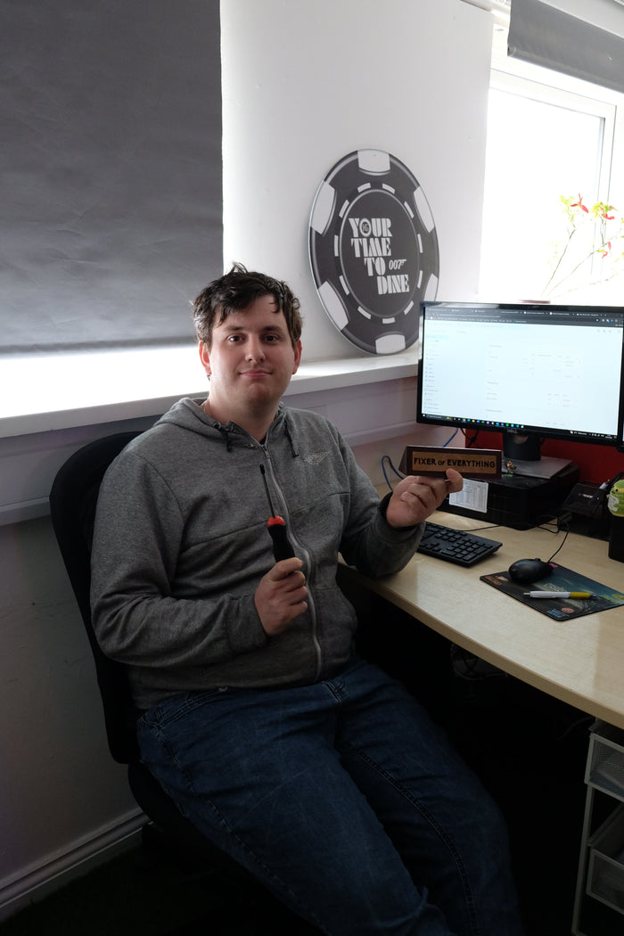 Person sitting at a desk with a computer setup, holding a remote control.