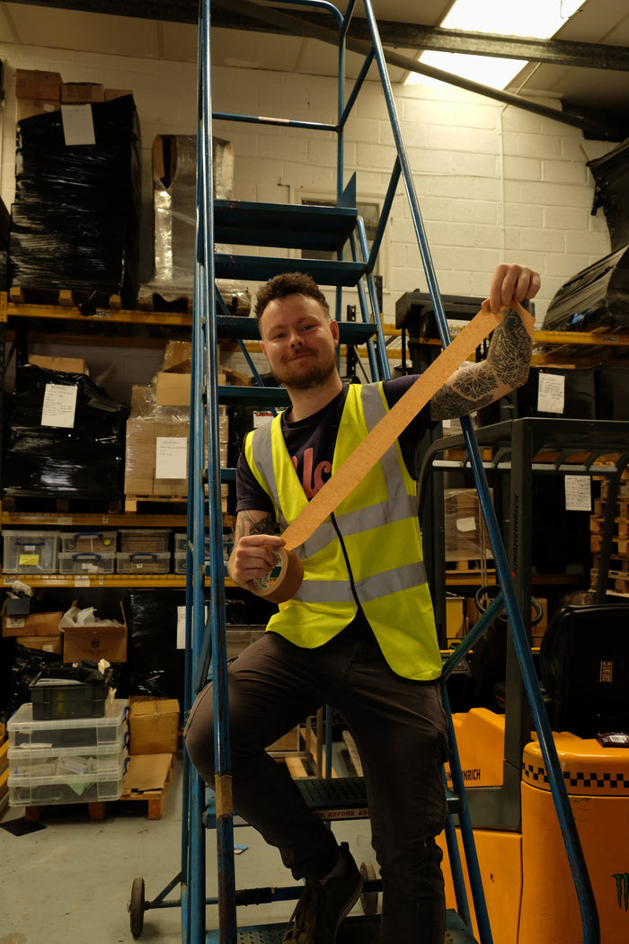 Person in a warehouse setting holding a long wooden plank