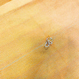 Close-up of yellow fabric with a small metal object on it