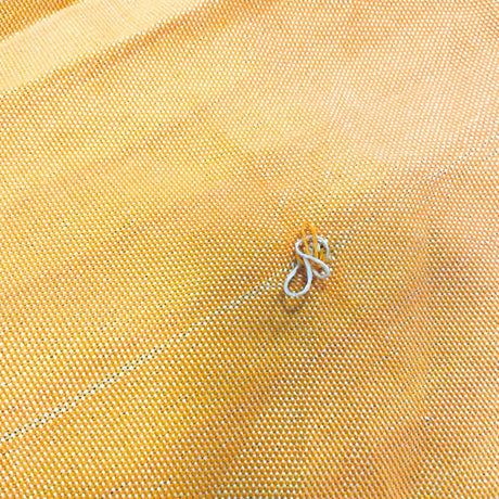 Close-up of yellow fabric with a small metal object on it