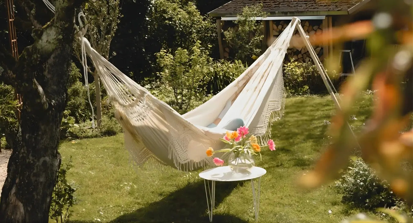 Beige hammock in a garden with a small table and flowers