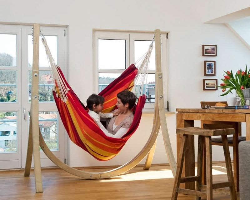 Two people in a colourful striped hammock in a modern living room.