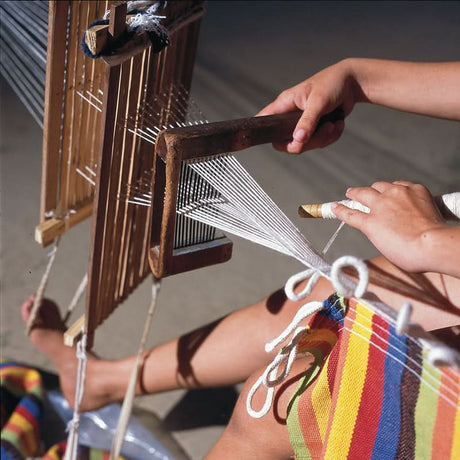 Person weaving with a loom, using a spray bottle to moisten the fabric.