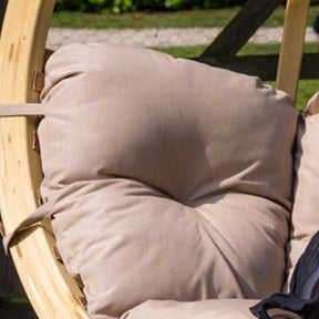 Close-up of a beige cushion on a wooden swing chair with a blurred outdoor background.