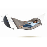 Person lying in a gray hammock with white straps on a white background