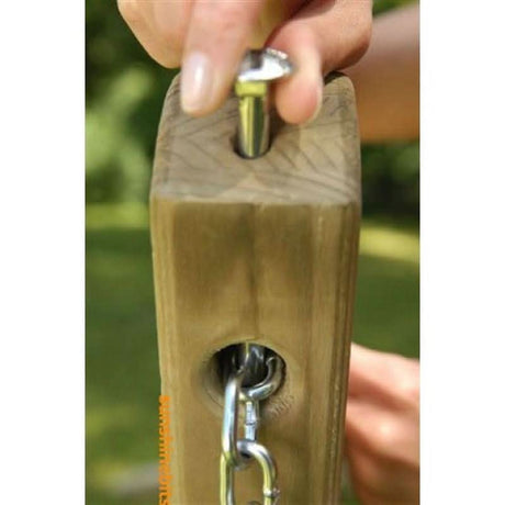 Wooden post with metal bracket and screw, held by a hand against a blurred green background