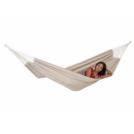 Woman relaxing in a beige hammock on a white background