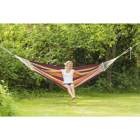 Woman sitting in a colourful hammock surrounded by greenery