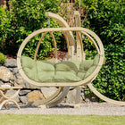 Hanging chair with green cushions in a garden setting