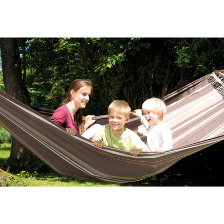 A woman and two children in a striped hammock outdoors