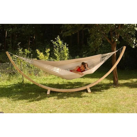 Person relaxing in a hammock under a tree in a garden setting