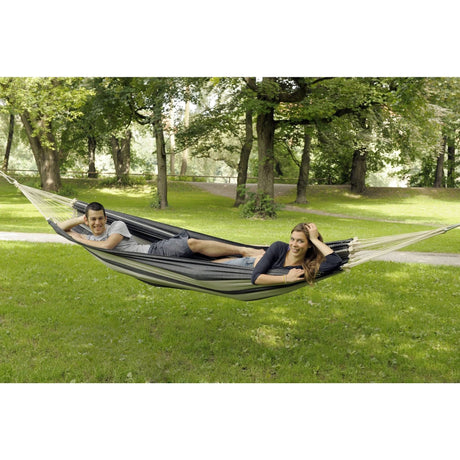 Two people relaxing in a hammock in a park setting.
