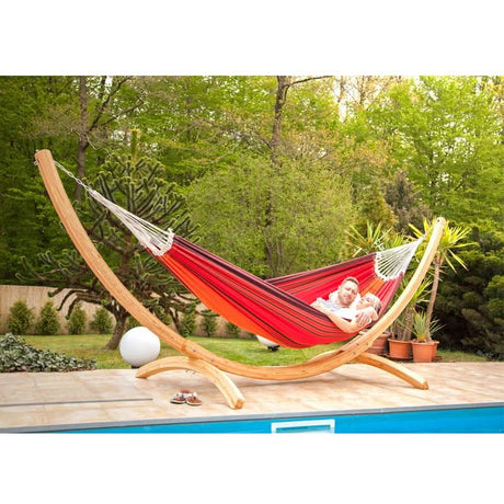 Red hammock on a wooden stand with a family in a garden setting.