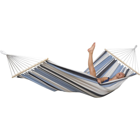 Person relaxing in a striped hammock on a white background