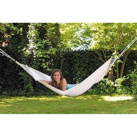 Woman relaxing in a white hammock in a garden setting
