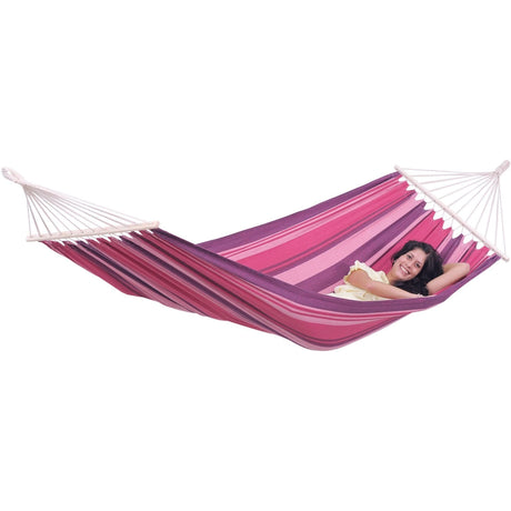 Woman relaxing in a pink and purple striped hammock on a white background
