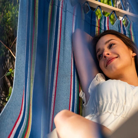 Woman lying in a striped hammock with clothes hanging in the background