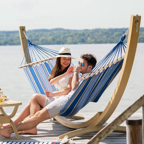 Couple relaxing in a striped hammock by a lake